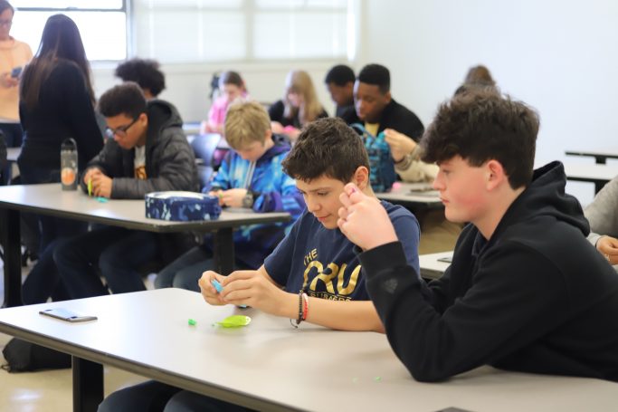 students using play-doh and dinosaurs molds to learn about injection molding.